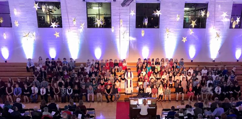 King of Grace students seated on bleachers for Christmas program