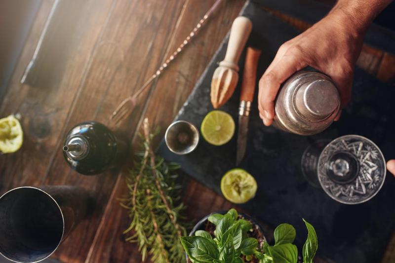 A bartender making a Rosemary and Basil Fizz cocktail.