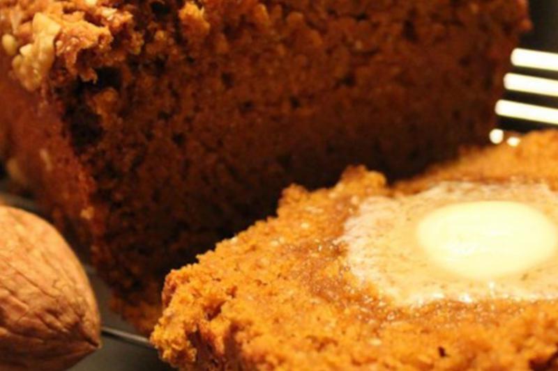 A closeup of butter melting on a slice of warm pumpkin bread.