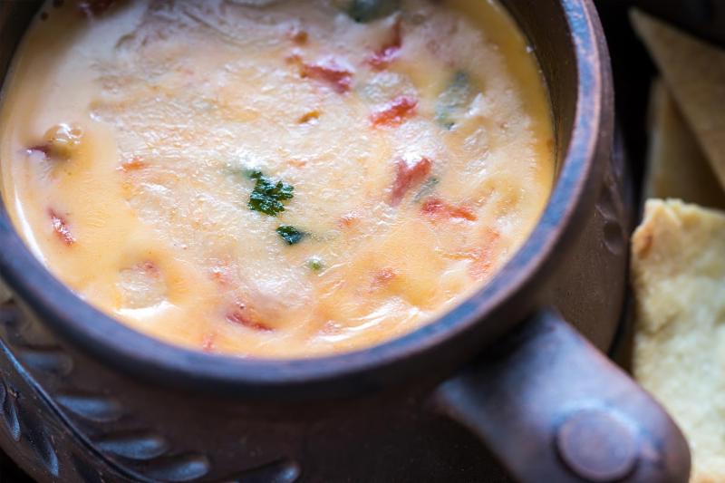 A top down picture of a three cheese dip with bacon and parsley.