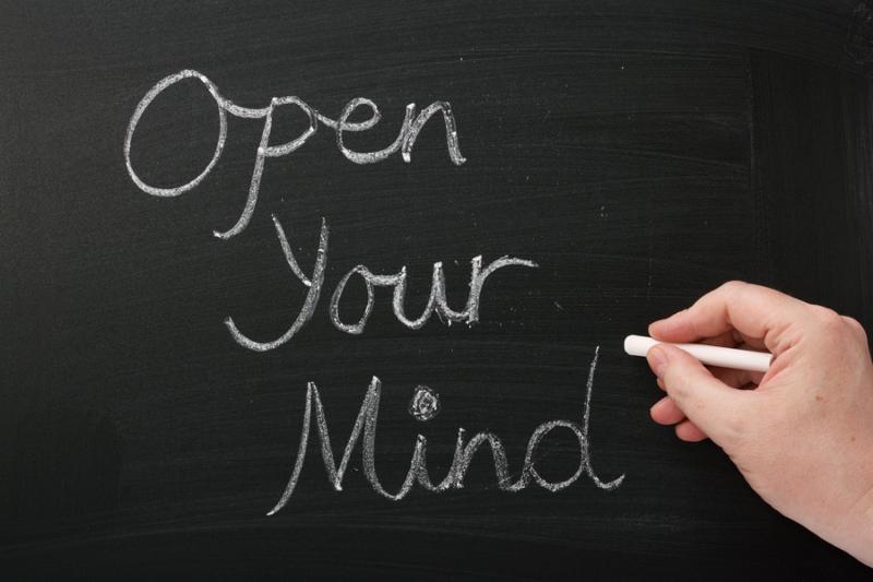 A hand writing Open Your Mind on a blackboard. A concept for having an open mind to new ideas,experiences and opportunity in our careers, education and personal lives