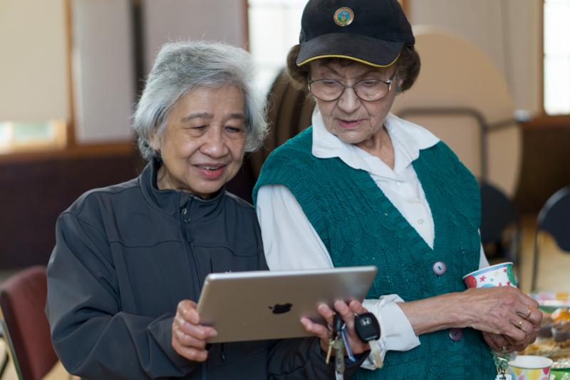 two seniors smiling at a computer tablet