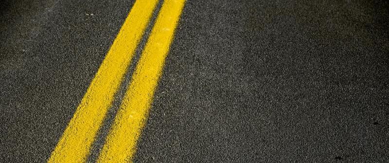 Road Pavement Backdrop - Black Road Pavement with Yellow Double Line. Travel and Transportation Background Theme.